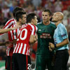 Los jugadores del Athletic rodean al árbitro del partido ante el Rapid