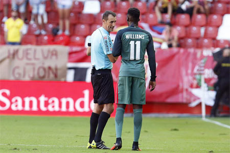 Iñaki Williams habla con el árbitro Clos Gómez durante el Sporting-Athletic